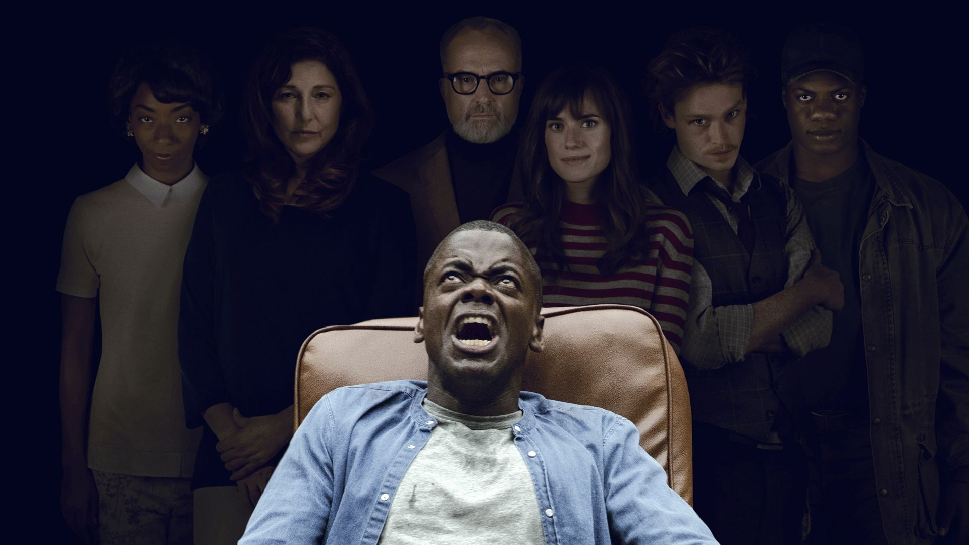 A BLACK MAN ON A CHAIR LOOKING HORRIFIED W/ A WHITE FAMILY BEHIND HIM
